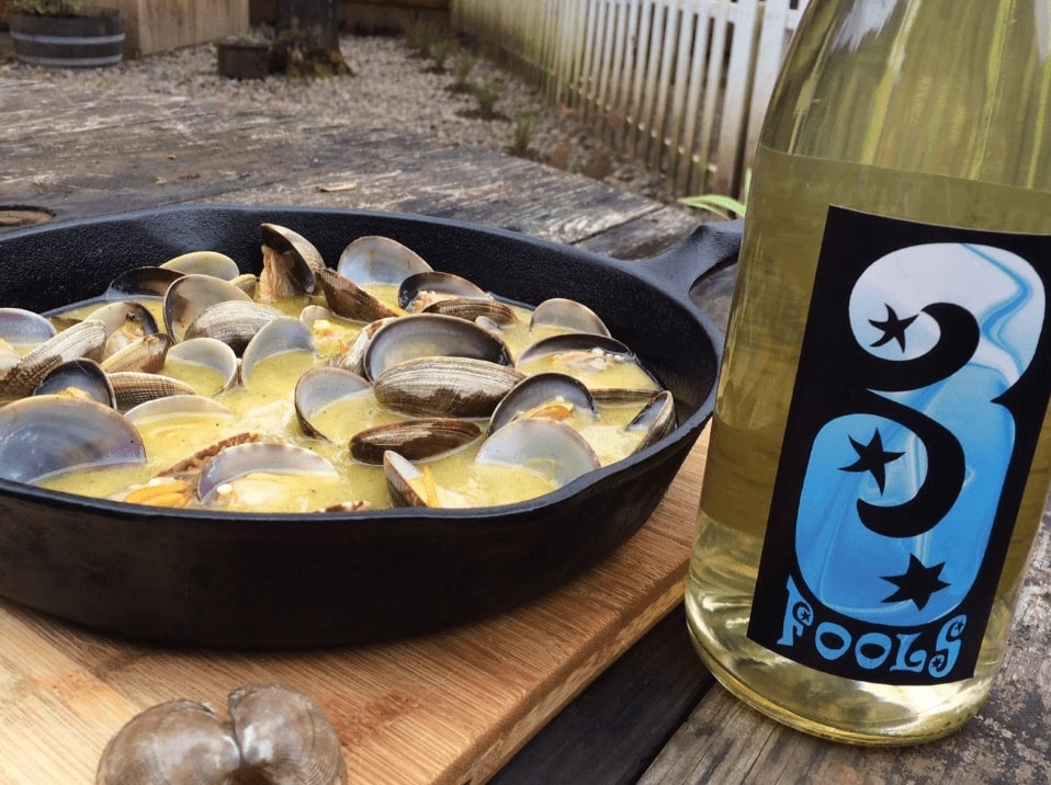 clams served next to a bottle of wine