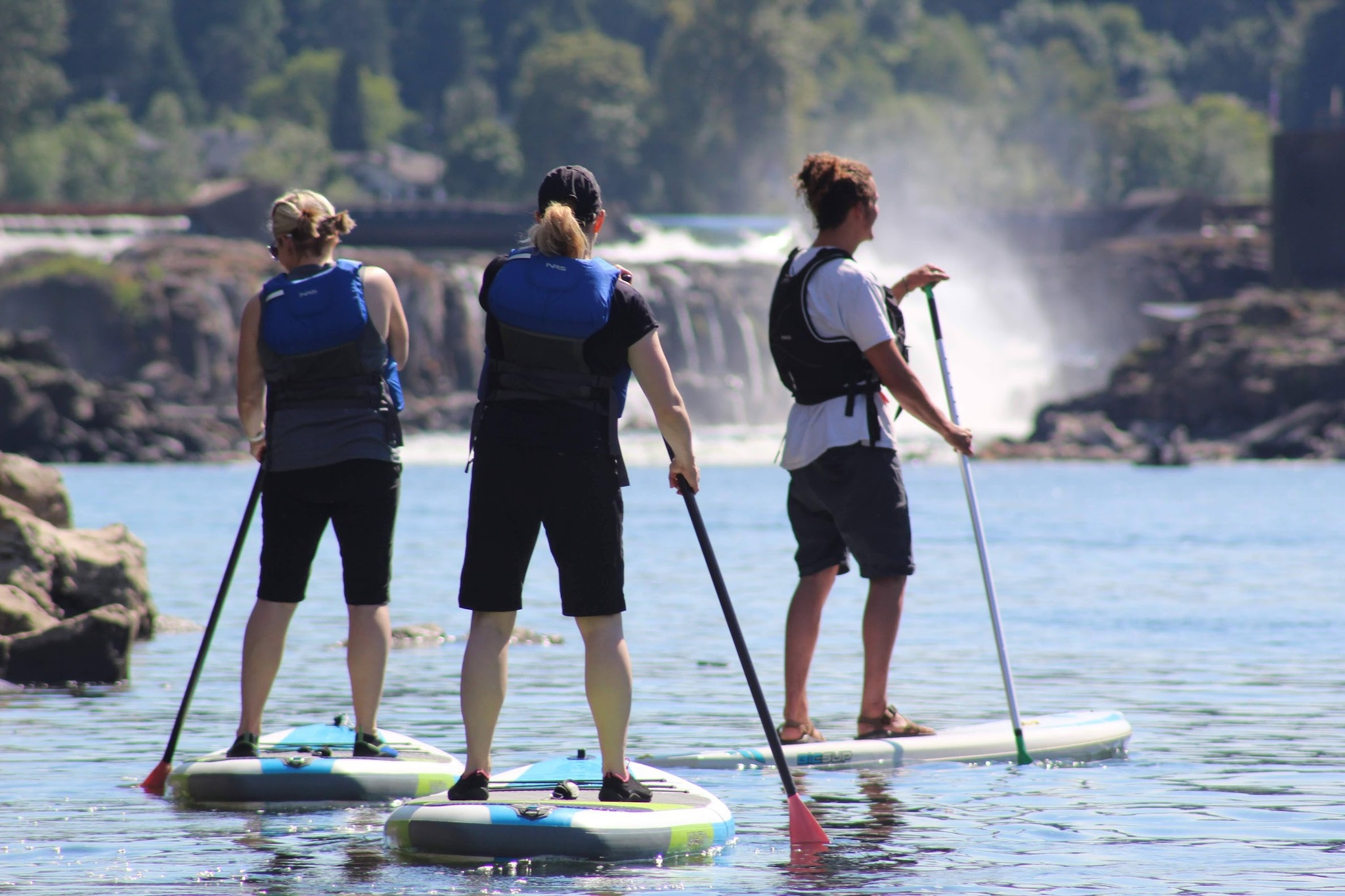 3 people on stand-up paddleboards look forward