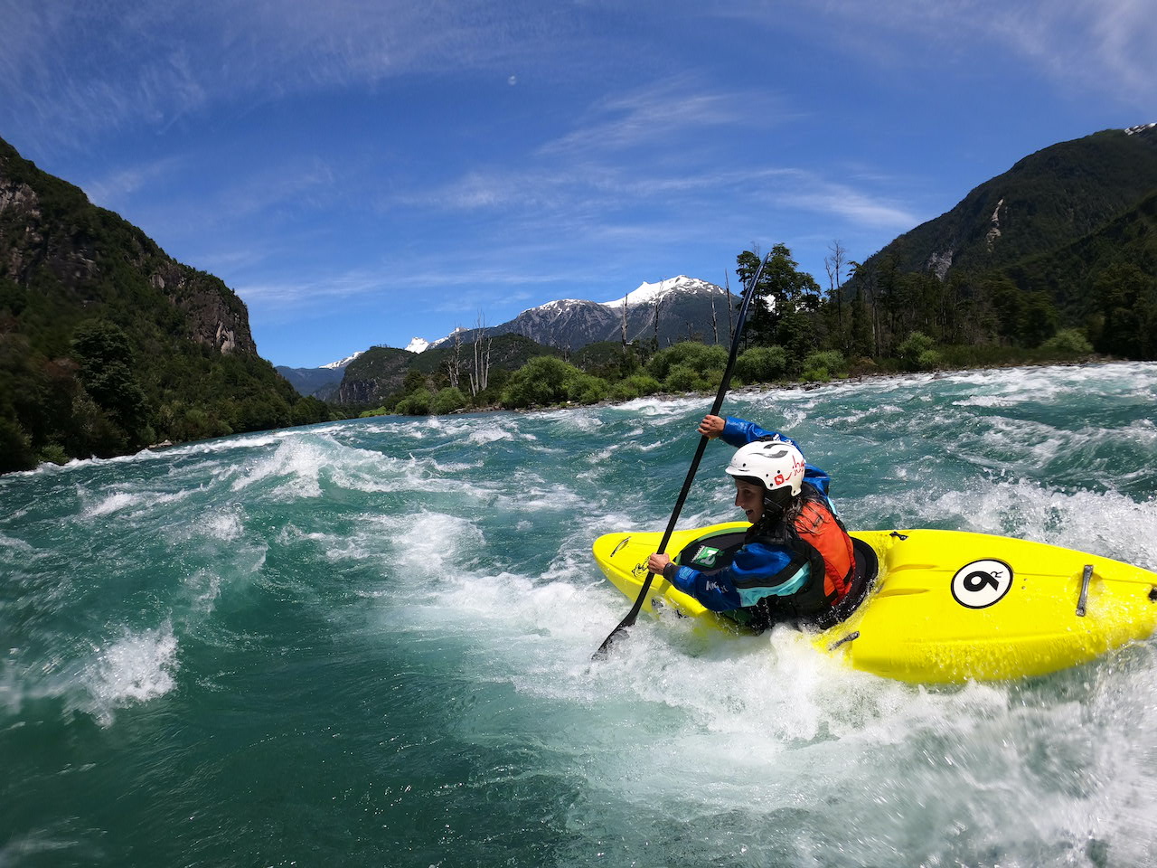 person in yellow kayak and helmet going down the river