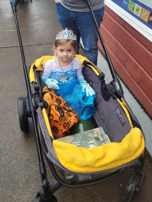 child dressed as princess rides in wagon for trick or treat event