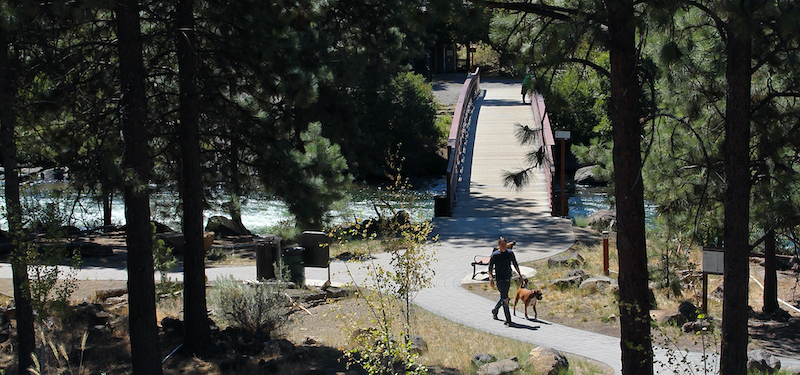 man and dog on the path at first street rapids park