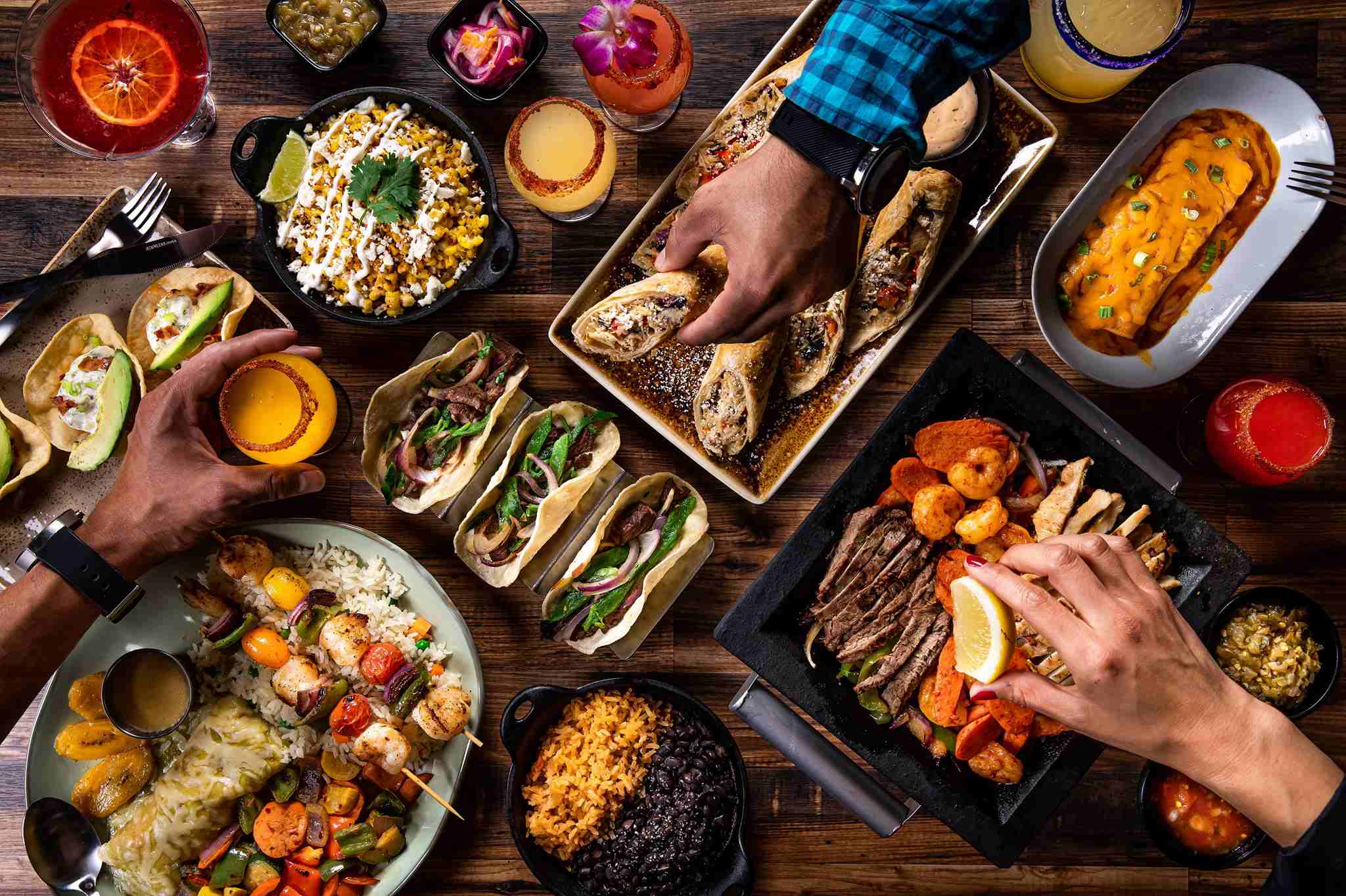 Hands reach across a table of food