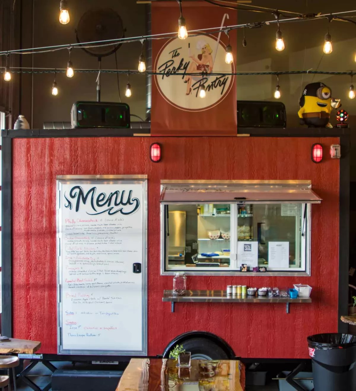 Side view of The Perky Pantry red food cart with large menu sign covering door and serving window with condiment shelf