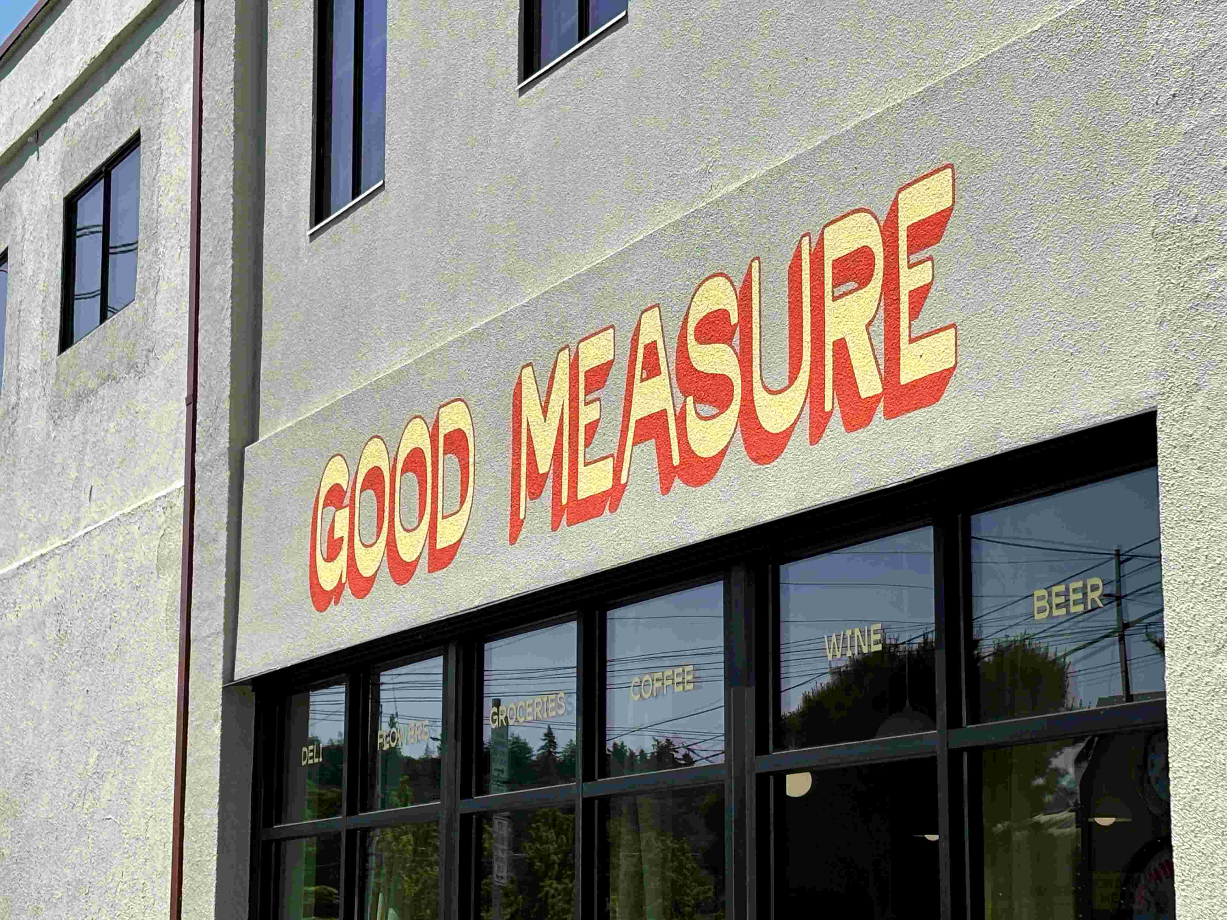Good Measure Cafe & Grocery's logo is painted in yellow and orange above their exterior windows.