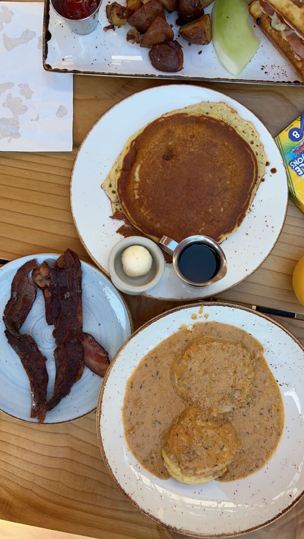 Pancakes, bacon, and biscuits and gravy brunch on a wooden table
