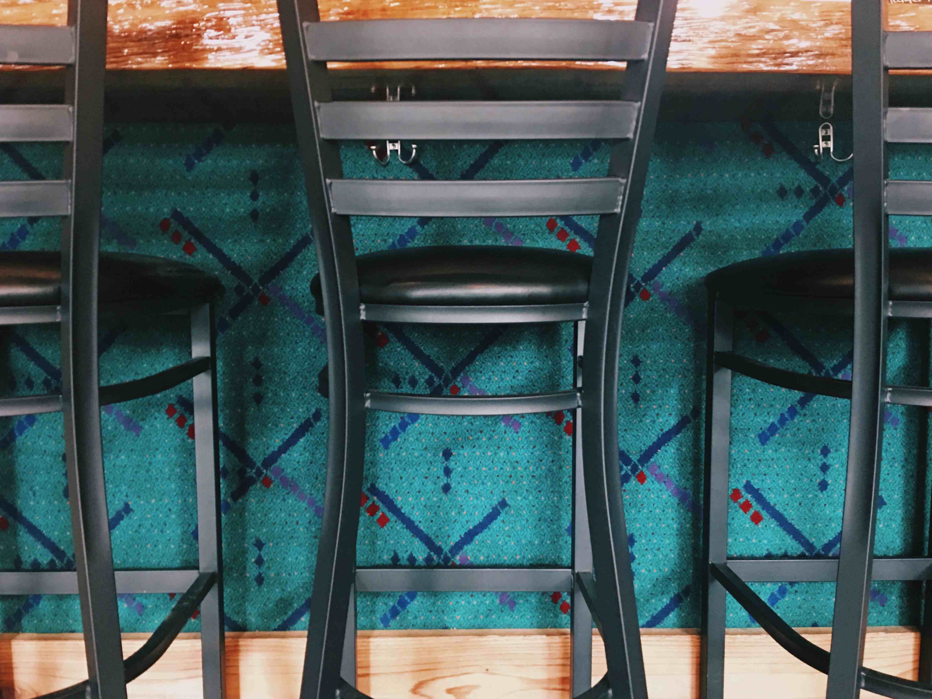 old PDX airport carpet decorates a bar front with several bar seats in front
