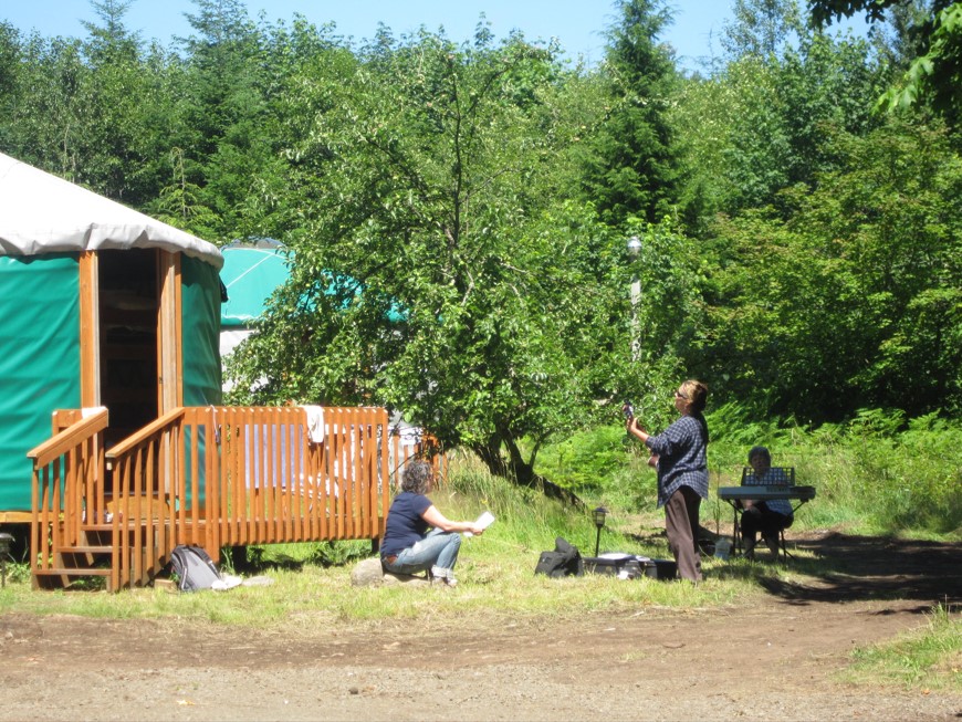 people gather to play music outside a yurt
