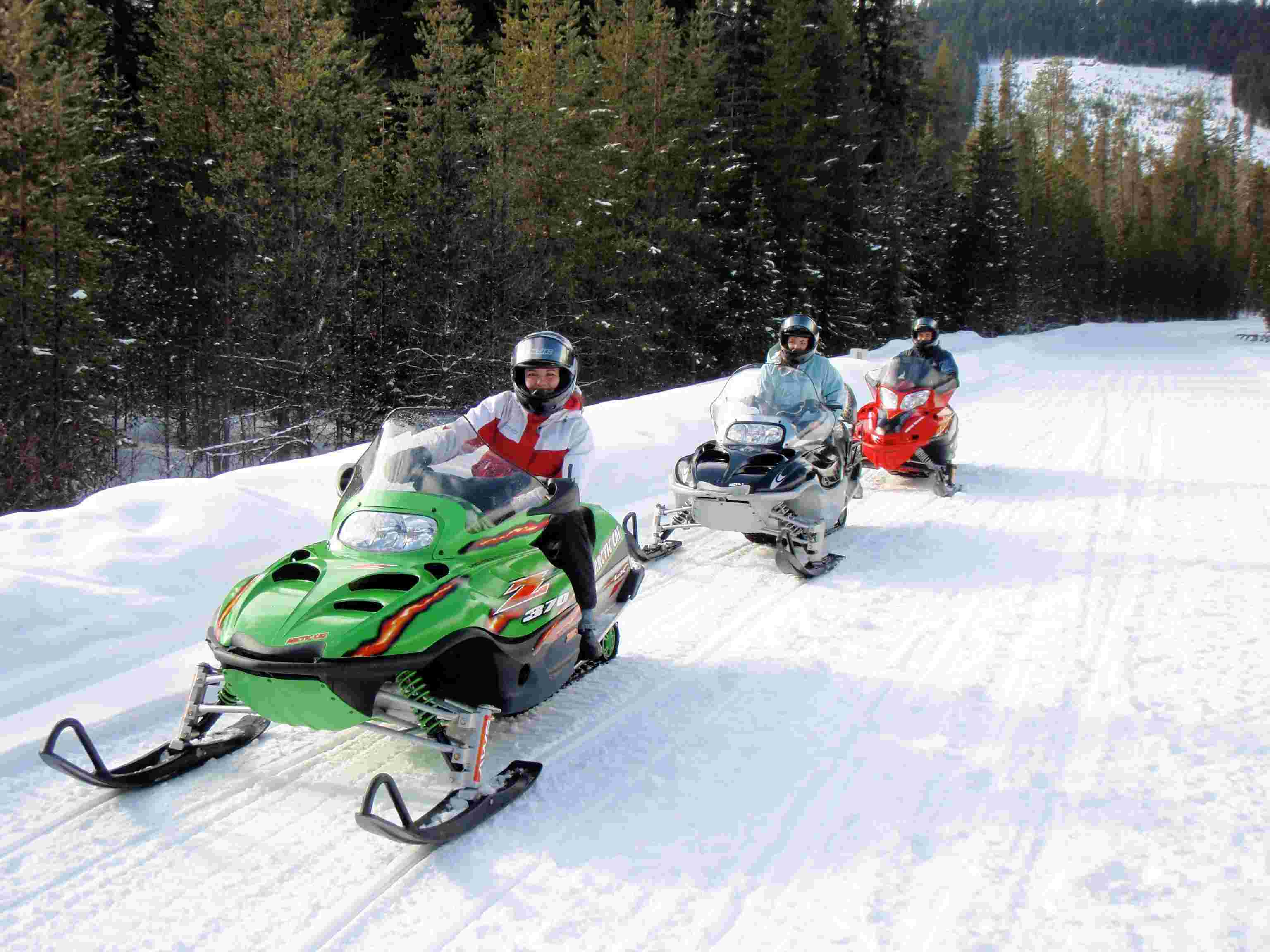 Three snowmobilers ride in a line at Froglake Snopark