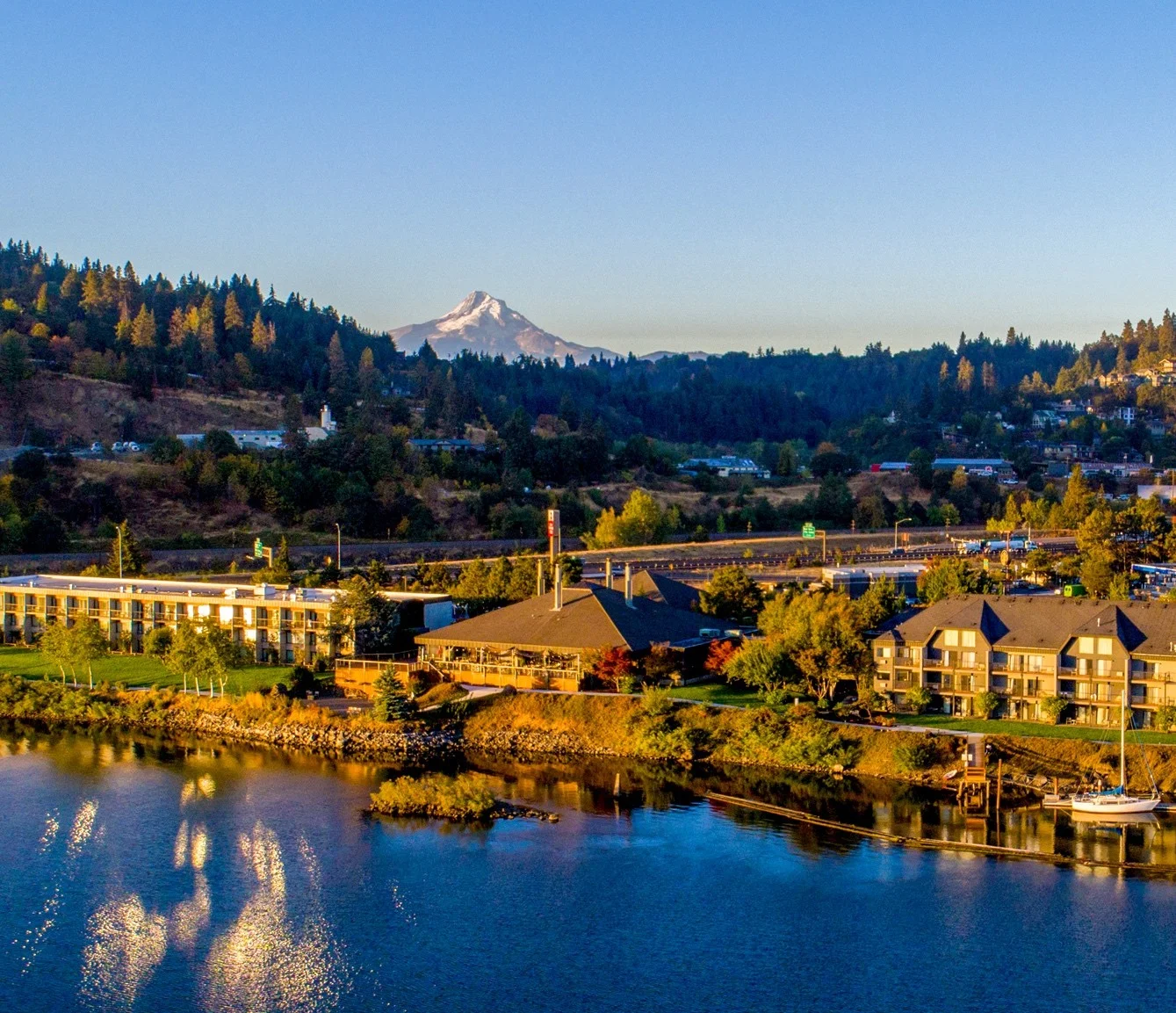 Buildings along the bank of a blue river with a mountain in the distant background.