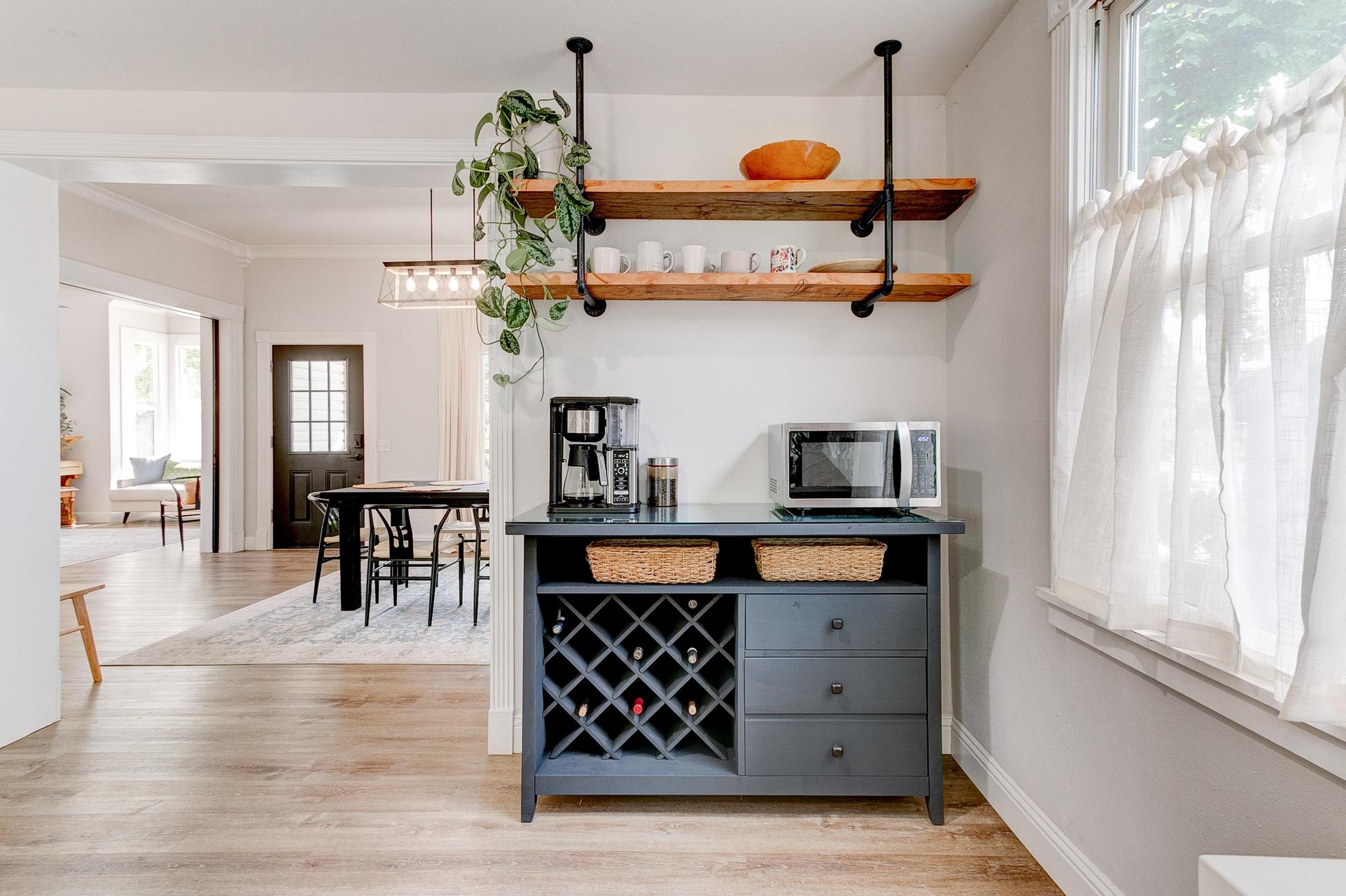 Dining area with a wine cabinet, coffee maker, and microwave with shelves above them