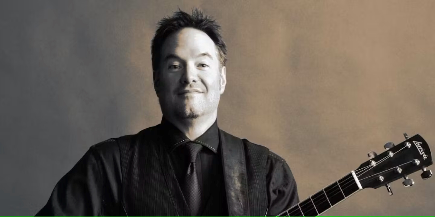 Person wearing a black shirt holding a guitar