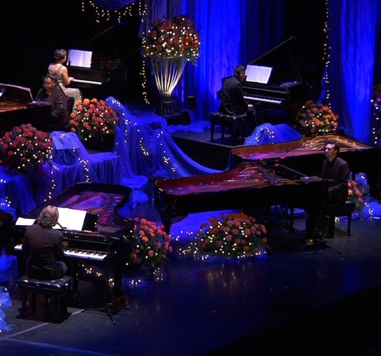 Multiple pianos on stage with flowers