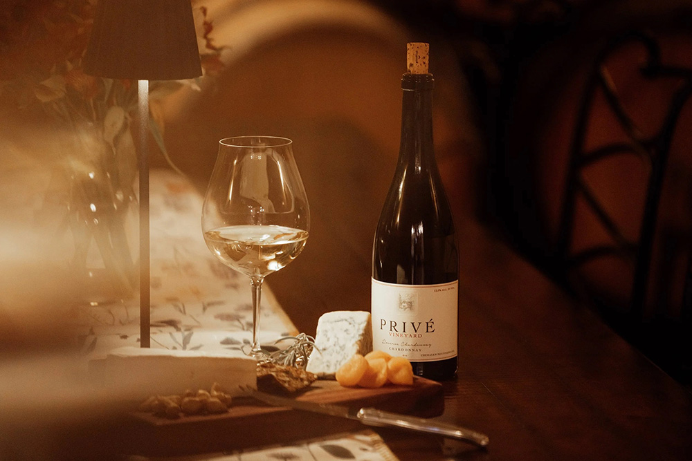 bottle of Privé wine next to stemmed wine glass