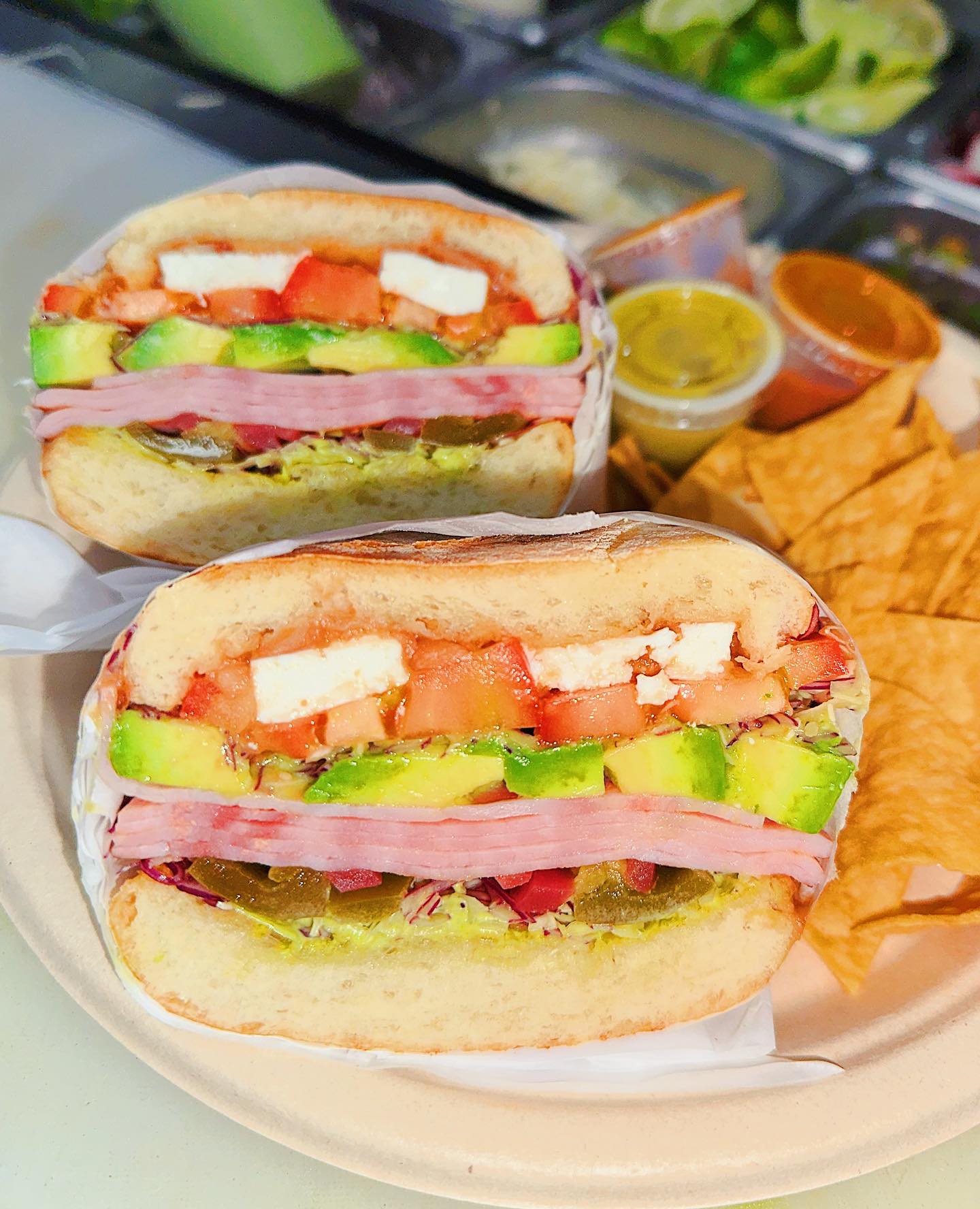 Sandwich cut in half with chips and salsa on the side