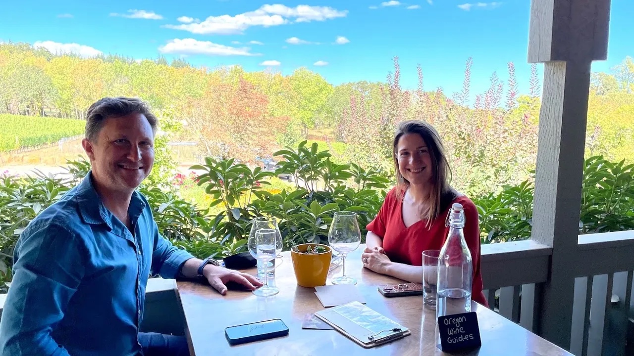 two people at a patio table overlooking a vineyard