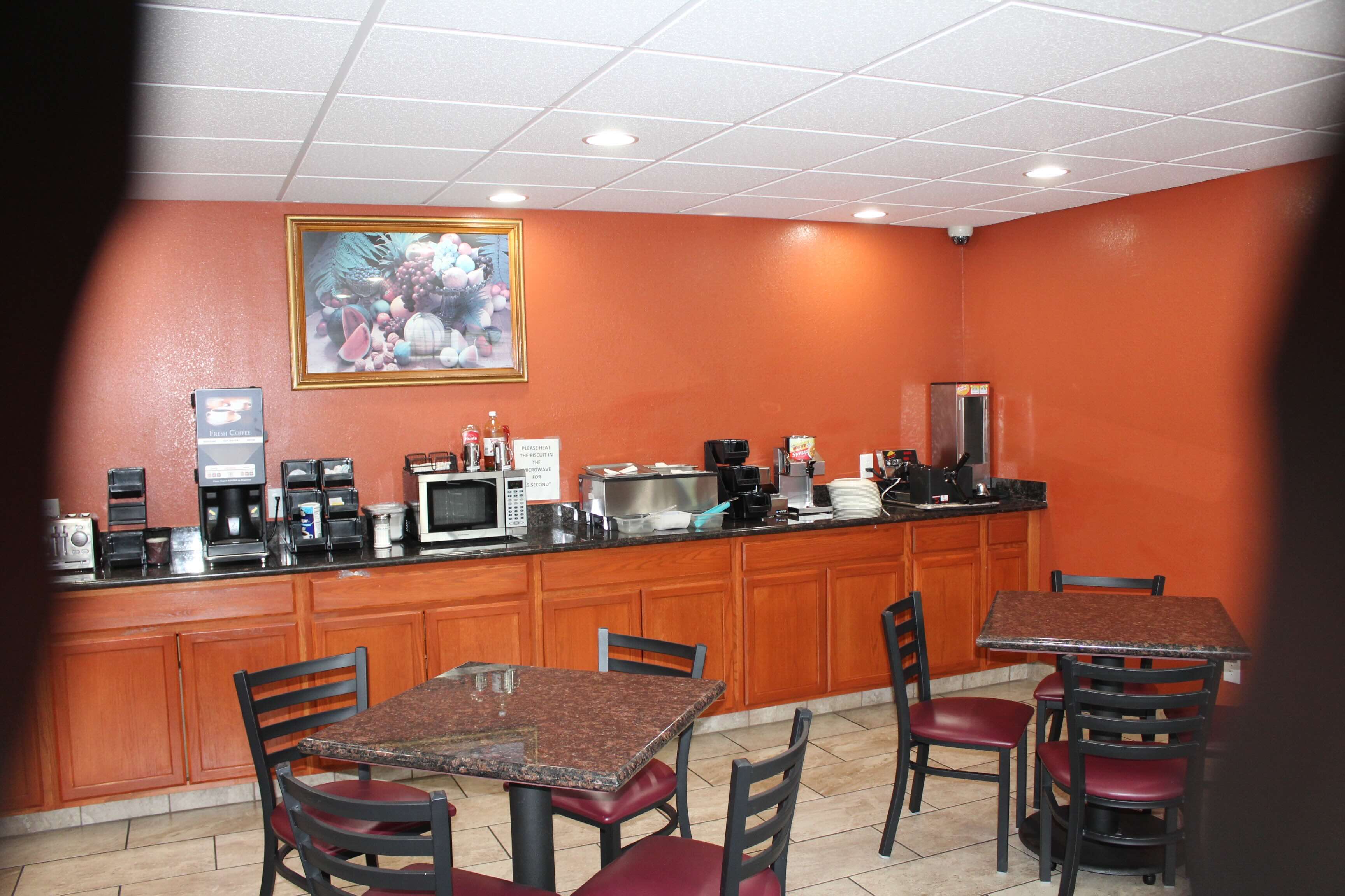 Hotel dinning area with appliance counter and two square tables with chairs.