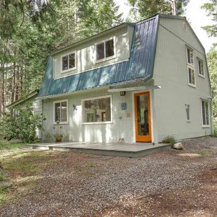 Green, two story home in the forest.