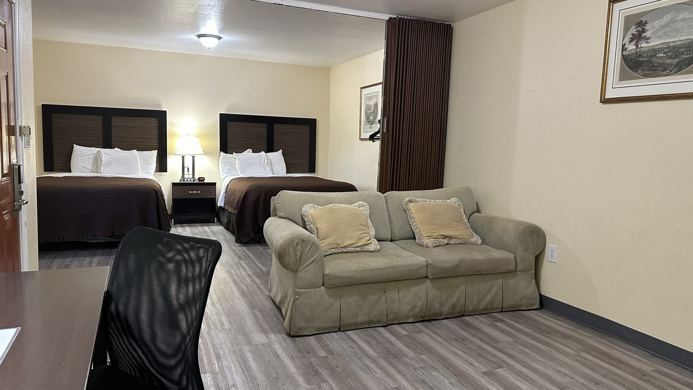 hotel room with two queen size beds and a tan couch.