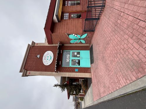 A brick paved walkway leads to a red brick building with vibrant baby blue doors.