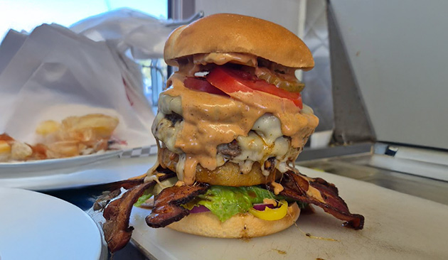 tall burger with bacon and melted cheese