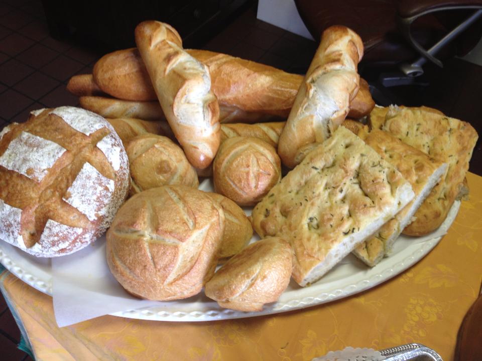 Empire Bakery platter of freshly baked artisan breads, baguettes, rolls and herb focaccia, showcasing a variety of rustic loaves and baked goods.
