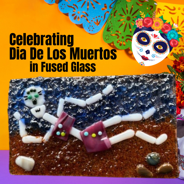 Fused glass artwork of a skeleton figure with text “Celebrating Dia De Los Muertos in Fused Glass” and colorful papel picado decorations.