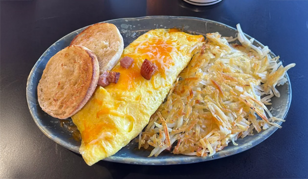 Omelet with melted cheese, hash browns, and toast on a plate.