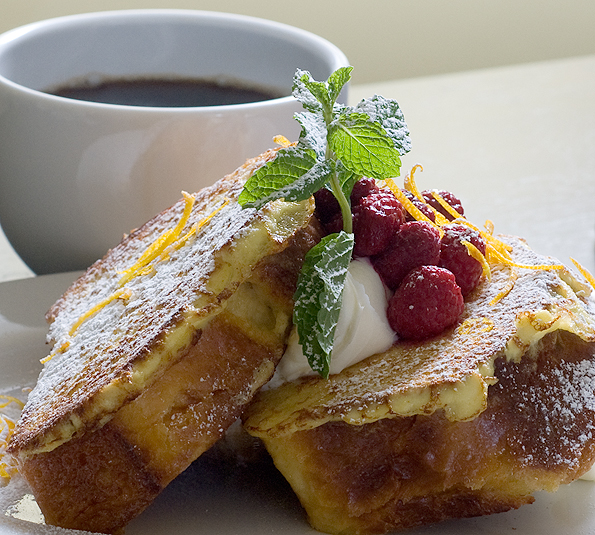 Cape Arago Cafe and Espresso serves French toast topped with powdered sugar, fresh raspberries, whipped cream and mint, paired with a cup of coffee.