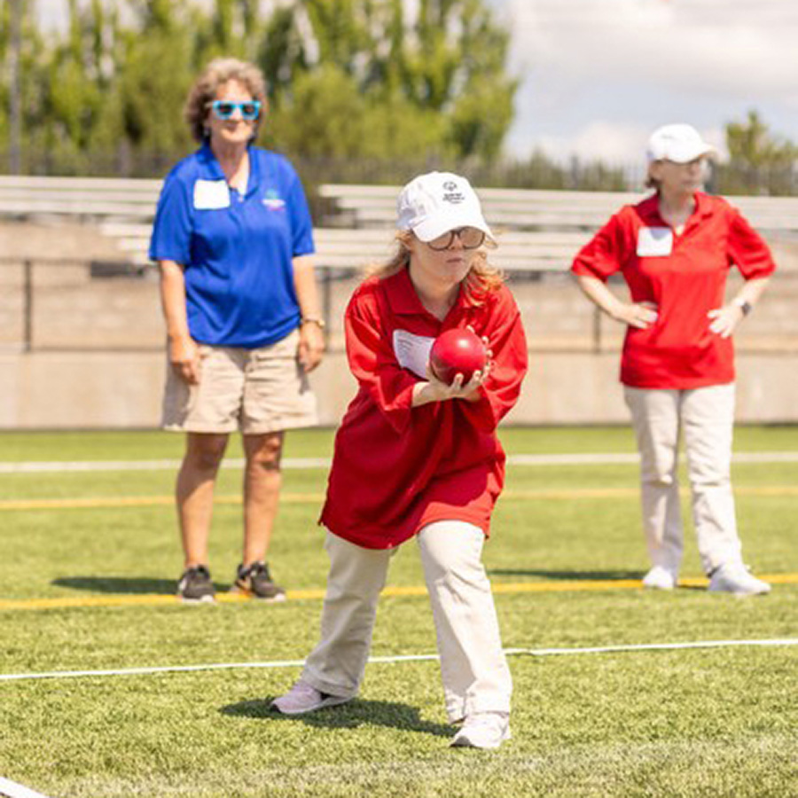 two kids playing bocce ball with an adult looking on