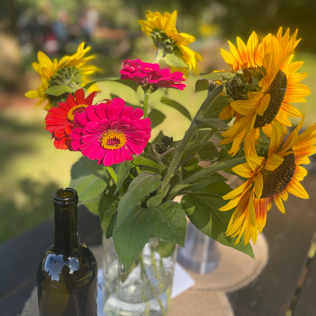 a clear glass holding a bunch of gerbera daisies and sunflowers