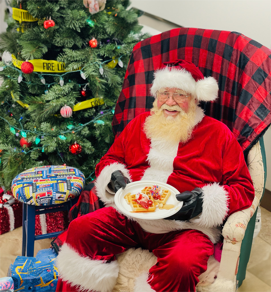 santa sitting on chair near christmas tree