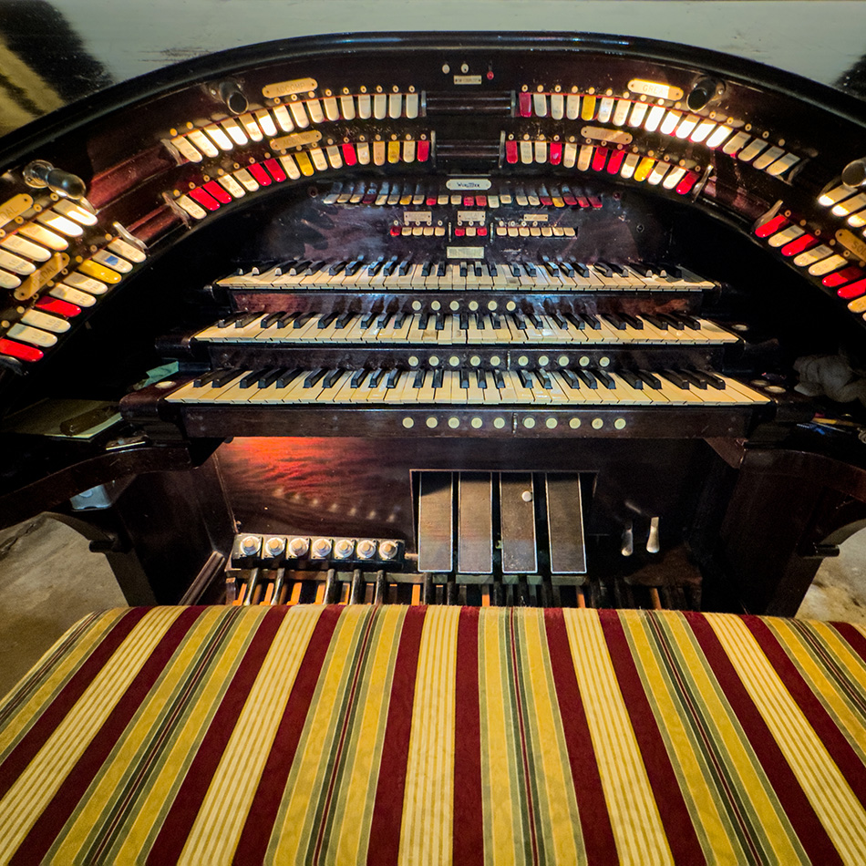 Close up image of an old wulitzer organ keys, pedals and bench