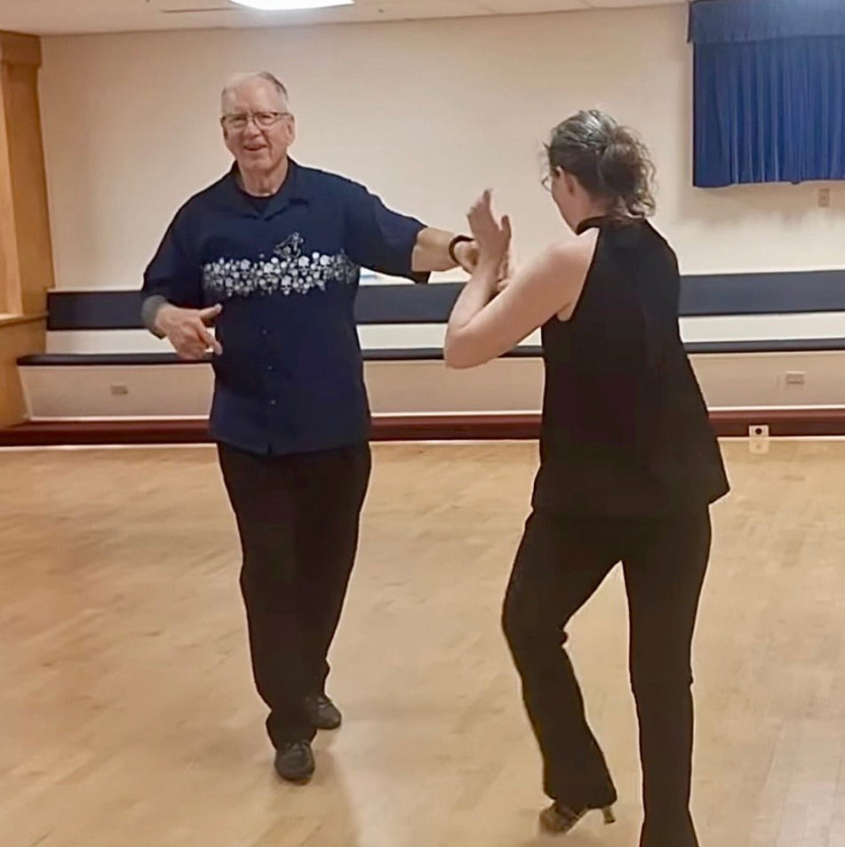 Two people dancing together in a ballroom studio