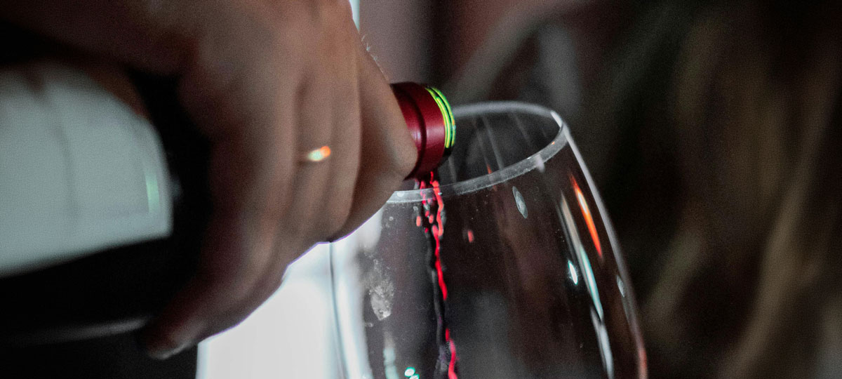 Close-up of red wine being poured from a bottle into a wine glass.  The background is softly blurred.