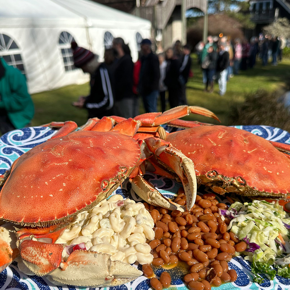two larger cooked crabs on top of a platter of baked beans and macaroni salad