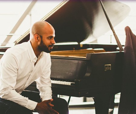 Artist Barron Ryan sitting in front of grand piano