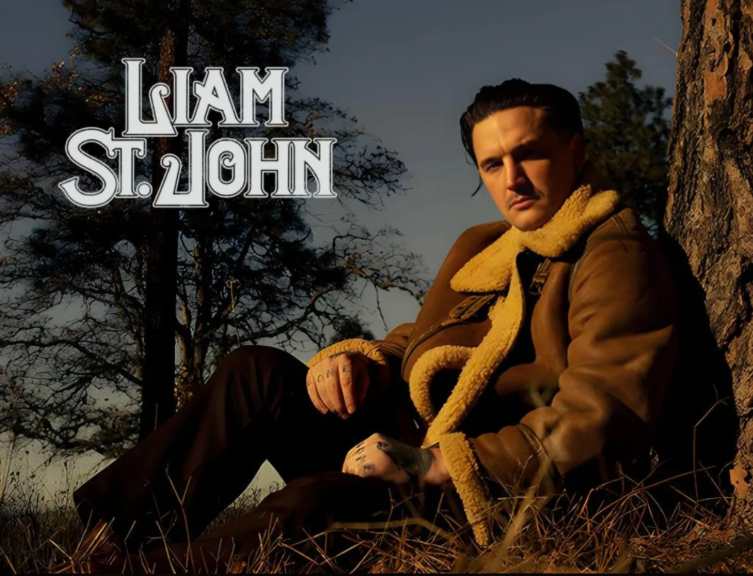 Liam St. John sitting against tree looking at camera