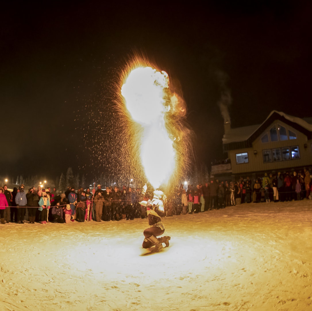 Fireworks artist blowing fire surrounded by a crowd of people