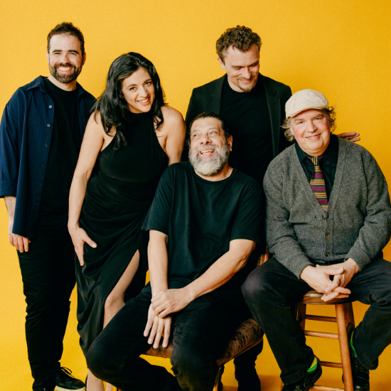 Five musicians in front of a yellow background