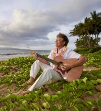 A guy playing guitar on a beach