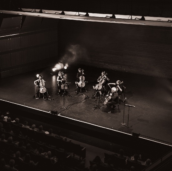 Five cello players on a stage