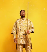 Chief Adjuah wearing gold holding an instrument