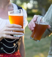 Up close image of two people holding beer glasses