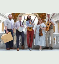 Four people, dressed up, smiling and holding instruments