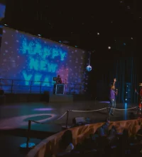 Happy New Year screen in front of a crowd of people