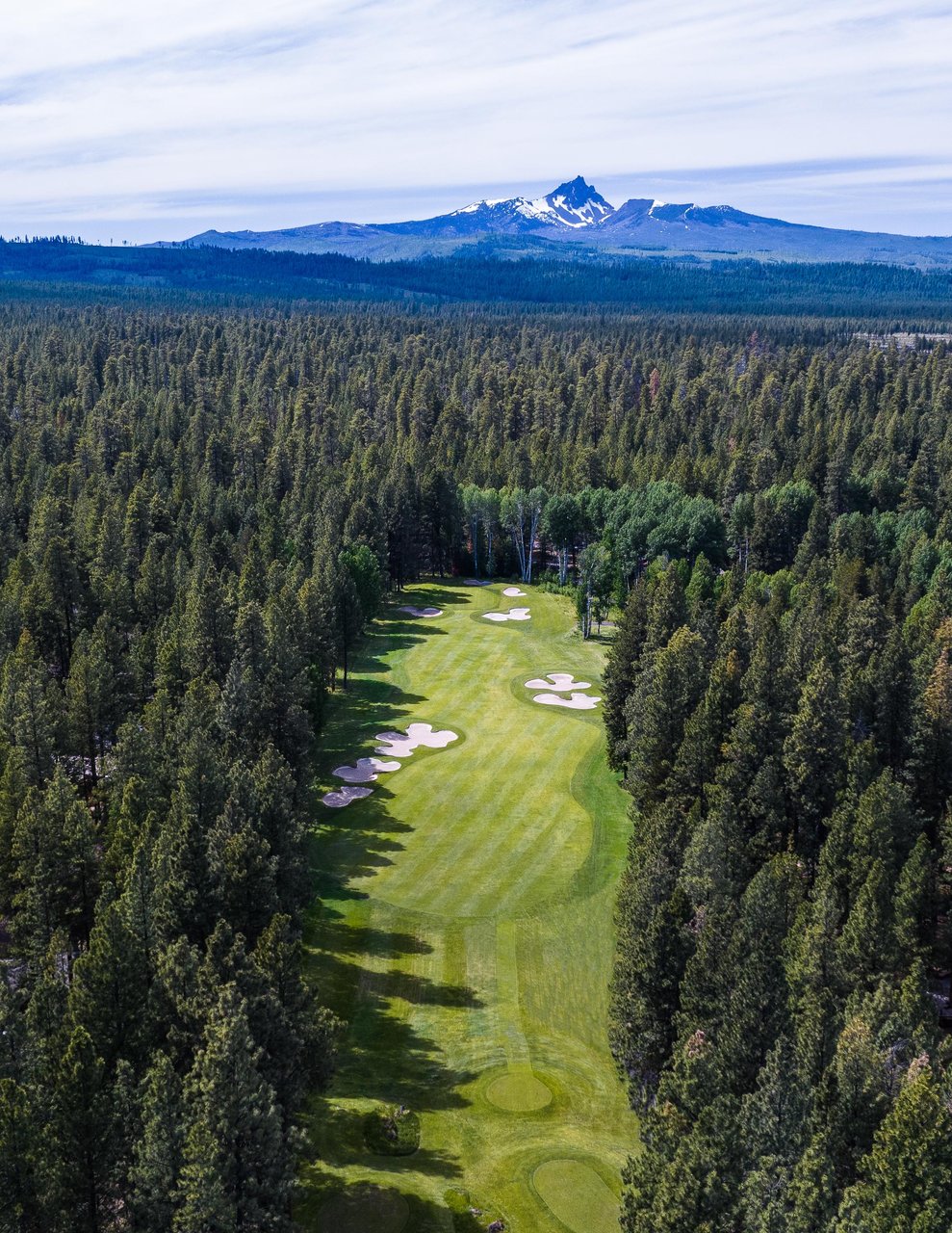 Golf course surrounded by trees with mountain in the background