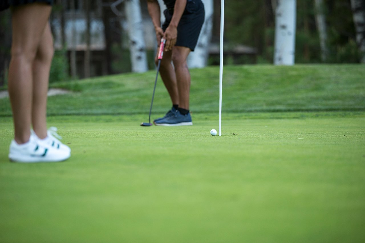 People putting on a golf green near the hole