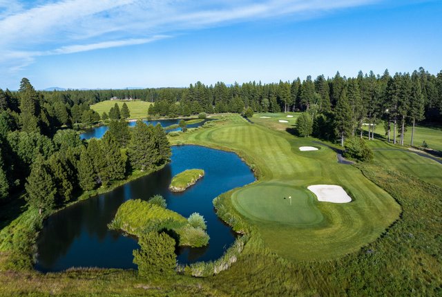 Golf course with water features and tress under a blue sky