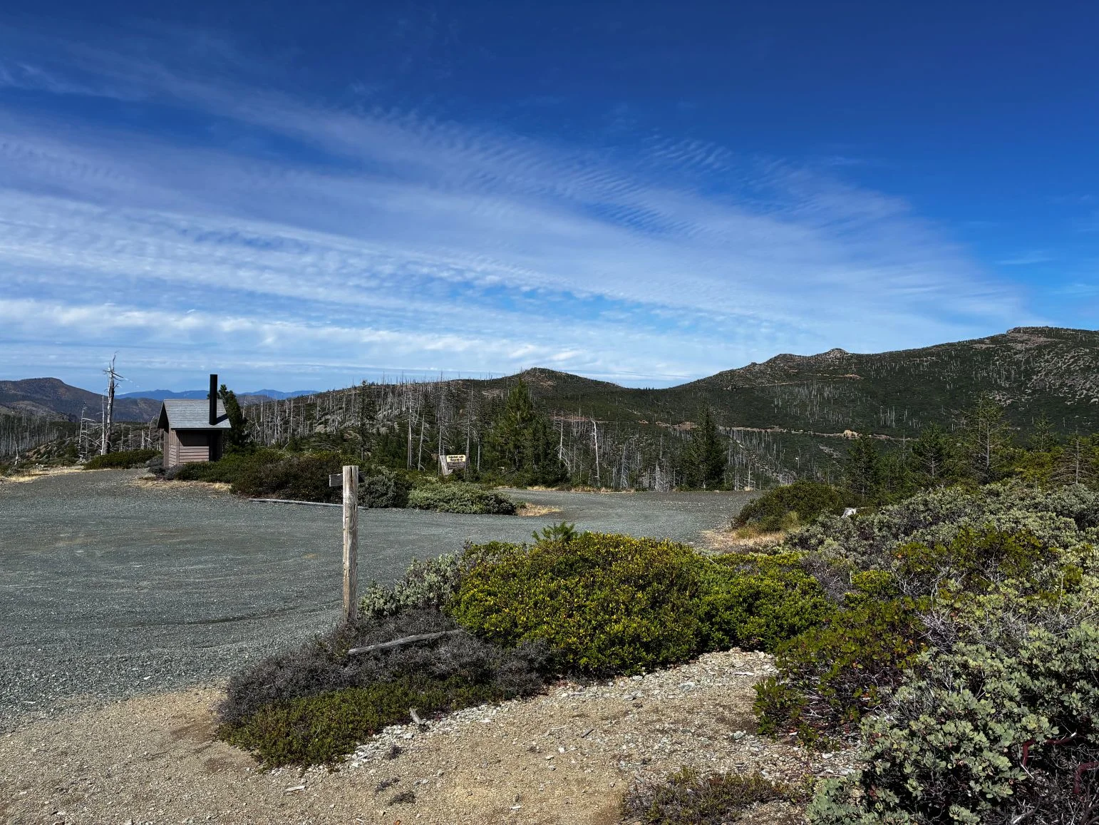 Gravel parking lot and out house.