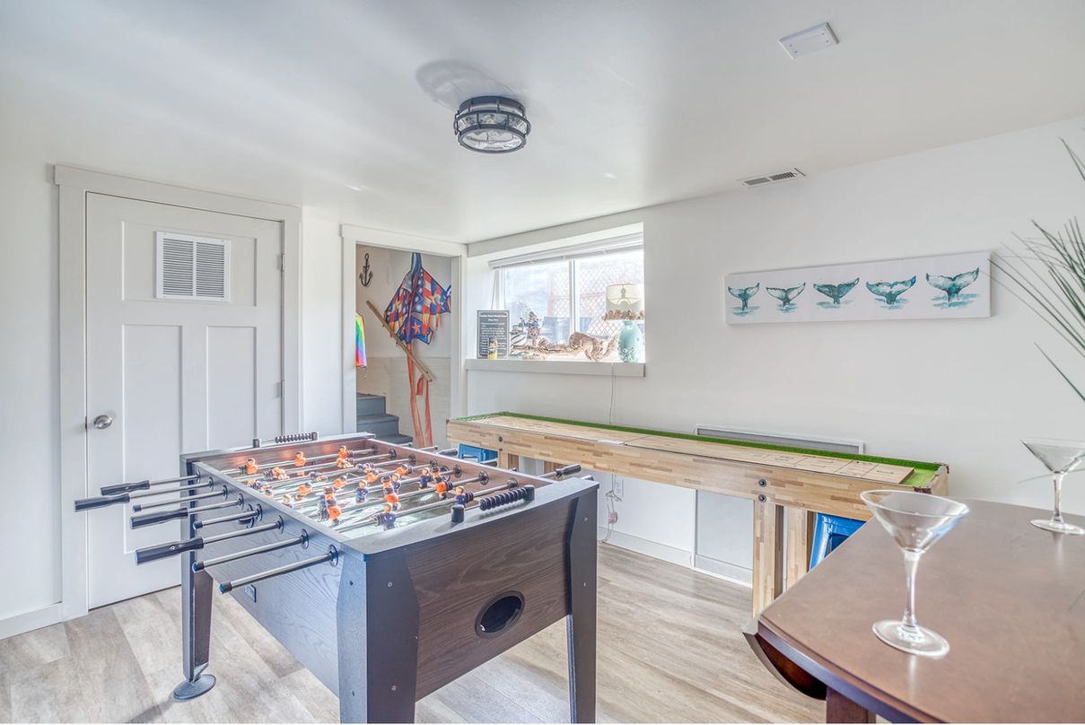 Game room showing a foosball table, shuffleboard table, and bar area.